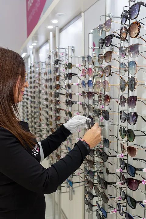 Una mujer mira gafas de sol en una óptica.