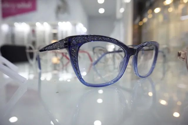 Un par de gafas azules colocadas encima de una mesa de cristal.