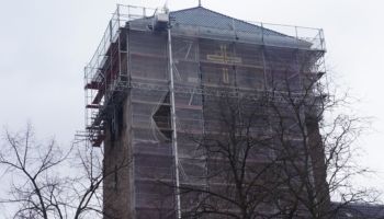 Ein großes Gebäude ist mit einem Gerüst bedeckt und im Hintergrund sind Bäume zu sehen.