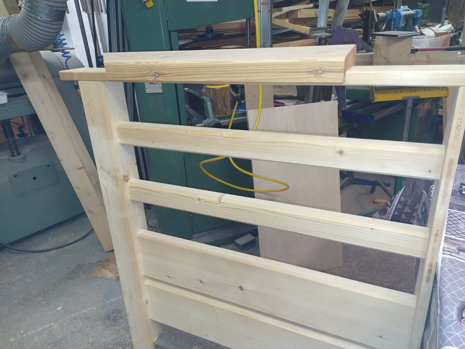 Une tête de lit en bois clair en cours de fabrication dans un atelier de menuiserie.