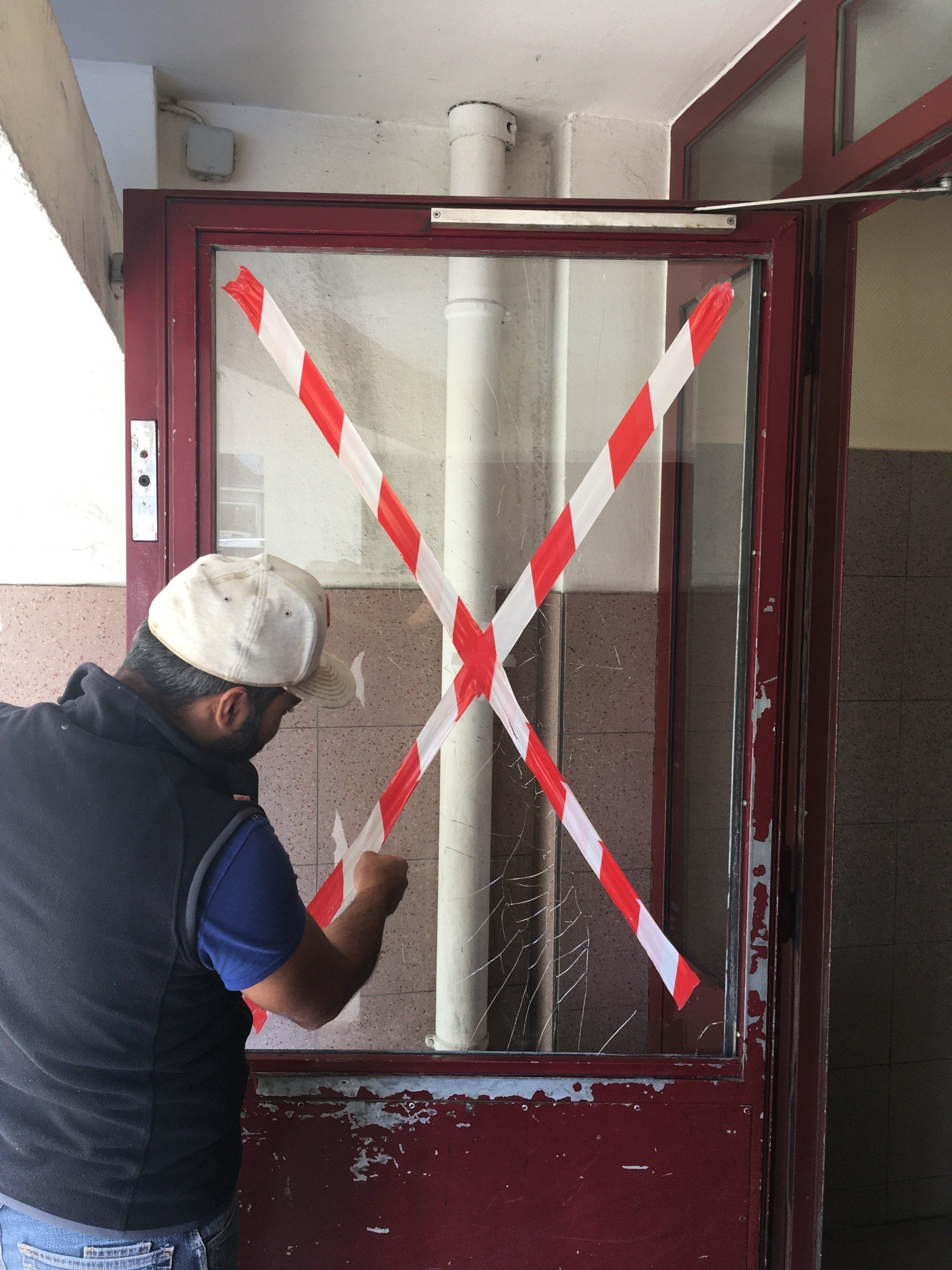 Un homme balise une vitre cassée