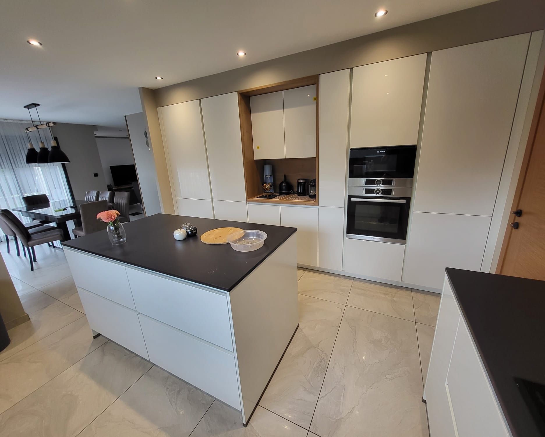 Un plan de cuisine montrant un îlot en bois foncé avec des tabourets de bar s'intégrant harmonieusement à un schéma filaire blanc.