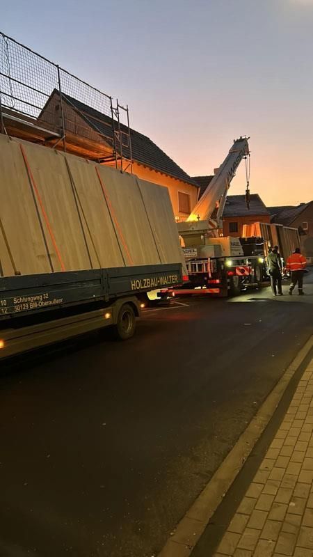 Ein Lastwagen transportiert ein großes Stück Holz eine Straße entlang.