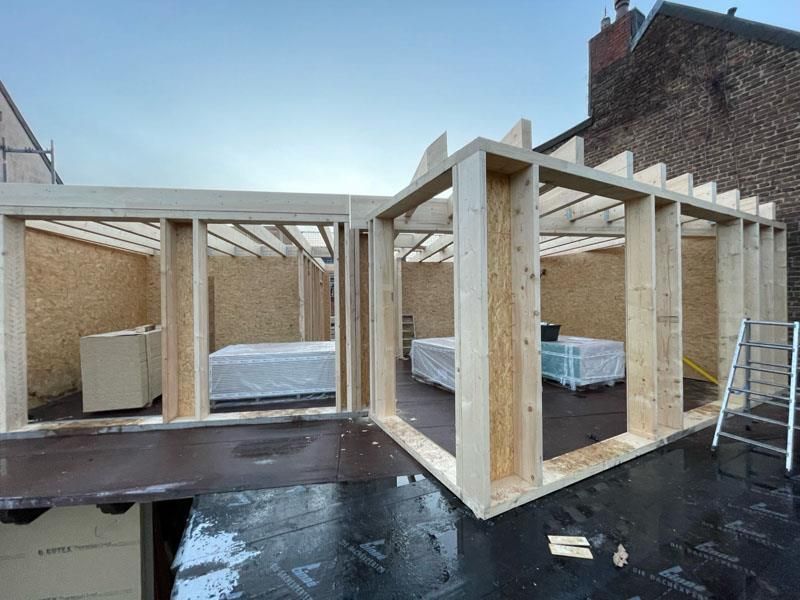 An der Seite eines Gebäudes wird eine große Holzkonstruktion errichtet.