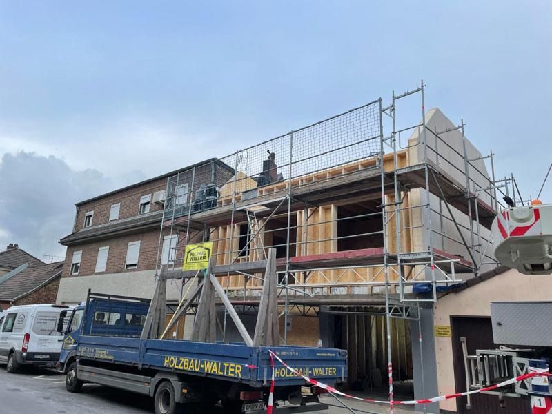 Ein blauer Lastwagen steht vor einem im Bau befindlichen Gebäude.