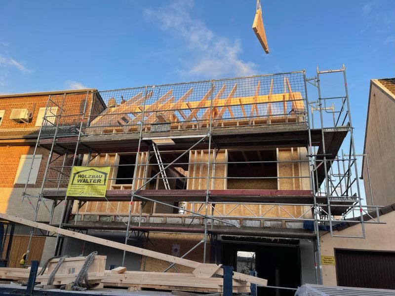 Mit Gerüst und Kran wird ein Haus gebaut.