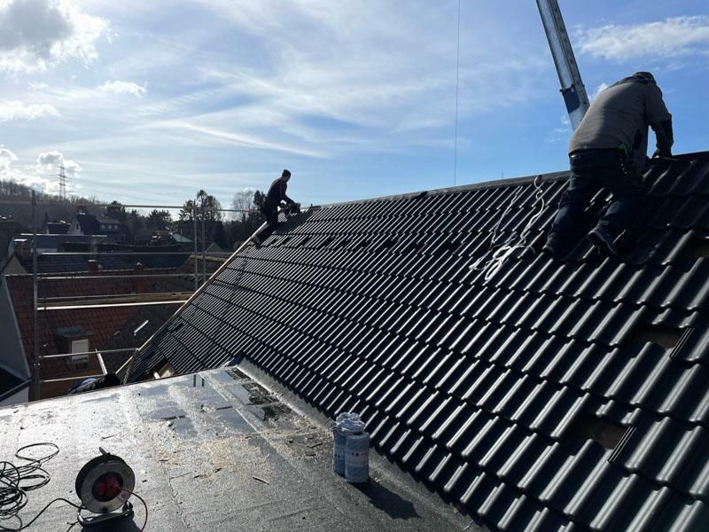 Zwei Männer arbeiten auf dem Dach eines Gebäudes.