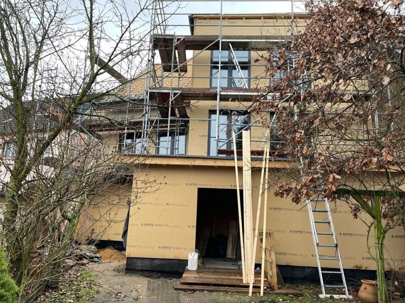 Mit Gerüst und Leiter wird ein Haus gebaut.