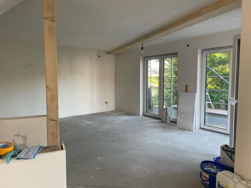 Ein großer leerer Raum mit vielen Fenstern und Farbeimern.