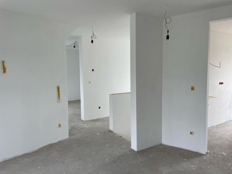 Ein leerer Raum mit weißen Wänden und Betonboden