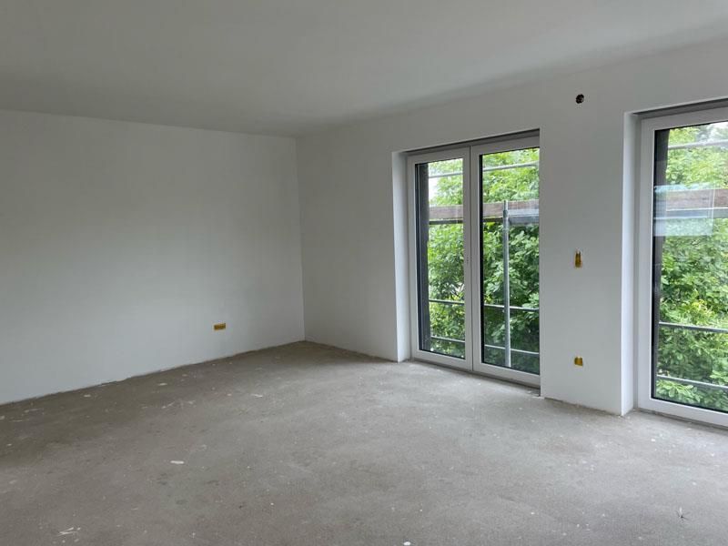 Ein leerer Raum mit vielen Fenstern und Teppichboden.