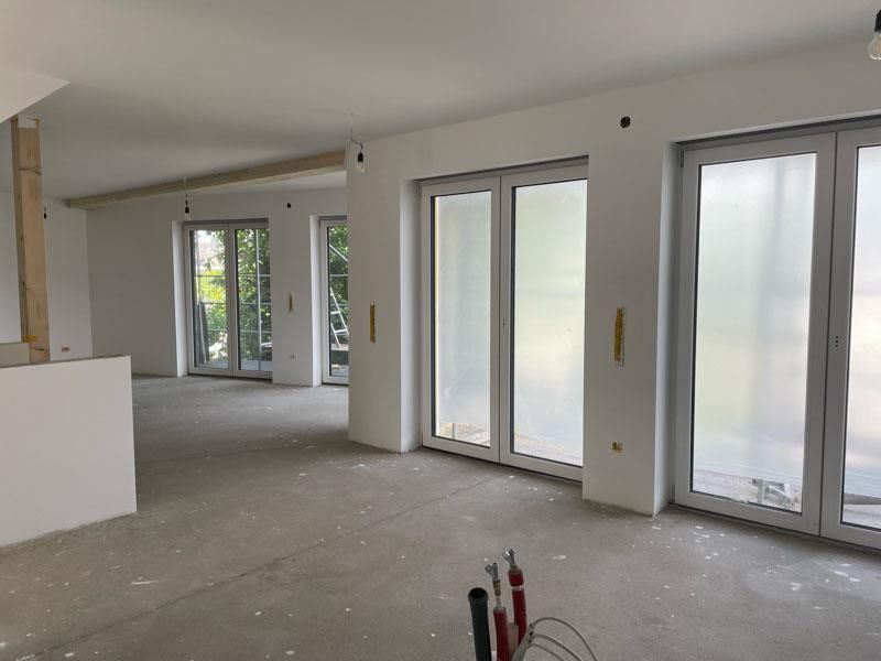 Ein großer leerer Raum mit vielen Fenstern und Türen.