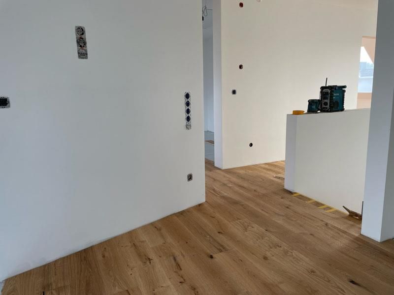 Ein Raum mit Holzboden und weißen Wänden.