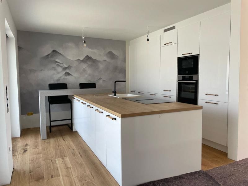 Eine Küche mit weißen Schränken und einer Arbeitsplatte aus Holz