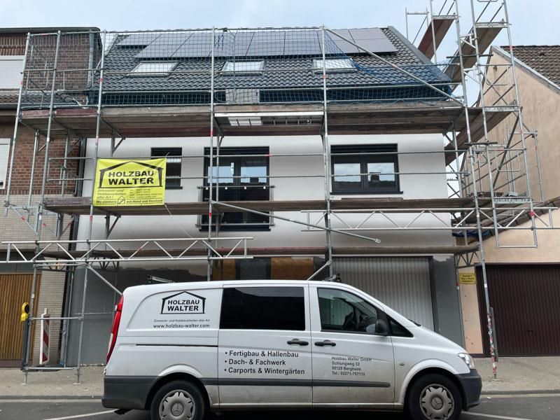 Ein weißer Lieferwagen steht vor einem Gebäude mit Gerüst.