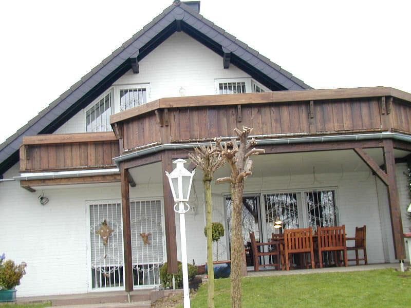 Ein weißes Haus mit einem großen Holzbalkon