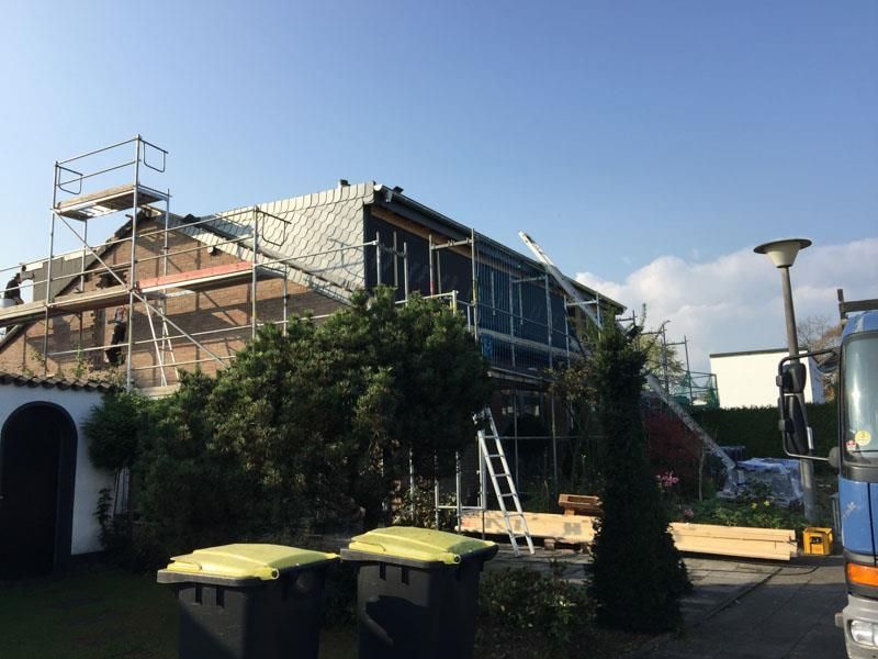 Ein im Bau befindliches Haus mit Gerüsten und Mülltonnen davor