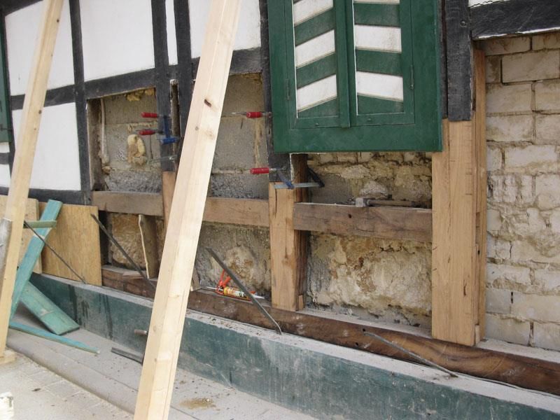 Eine Ziegelwand mit Holzbalken und einem grünen Fenster