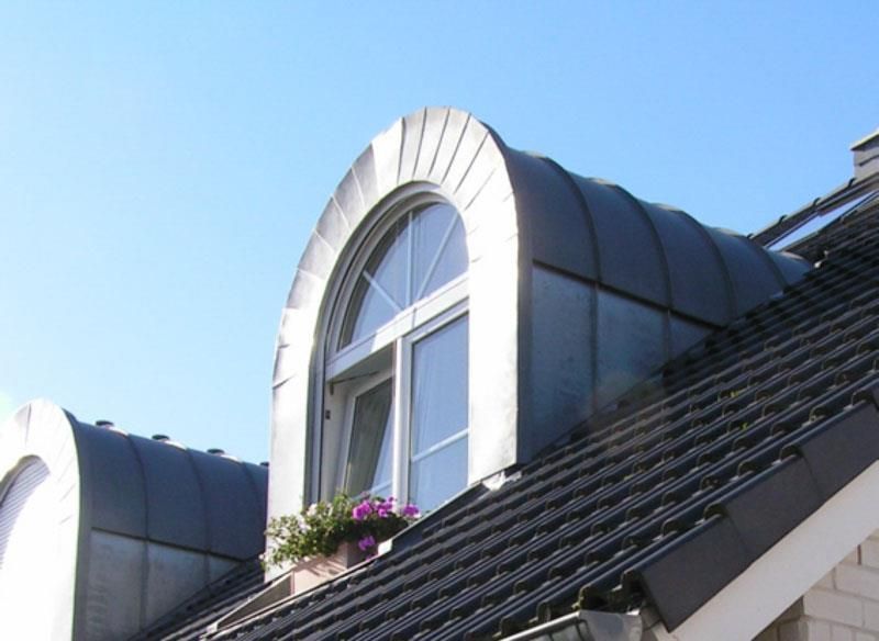 Ein Fenster auf dem Dach eines Gebäudes mit lila Blumen