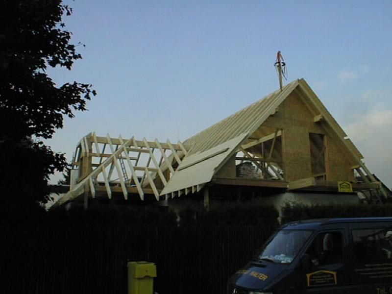Ein blauer Lieferwagen steht vor einem im Bau befindlichen Haus