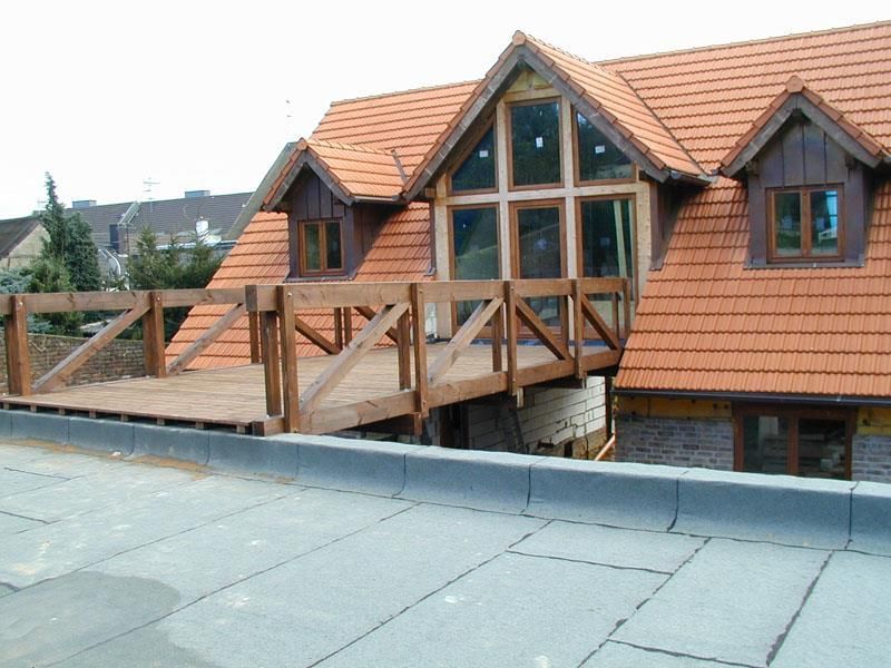 Ein Haus mit einer Holzterrasse und einem roten Ziegeldach