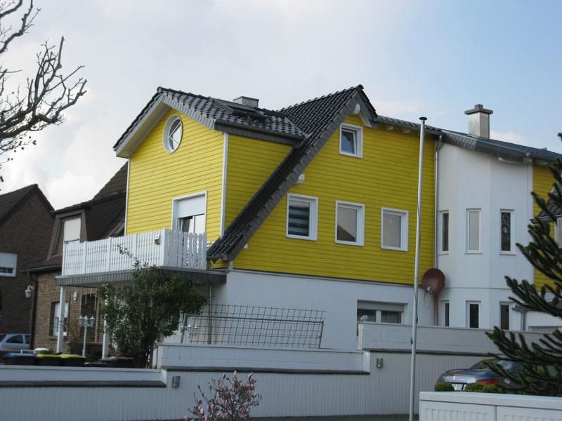 Ein gelb-weißes Haus mit einem schwarzen Dach