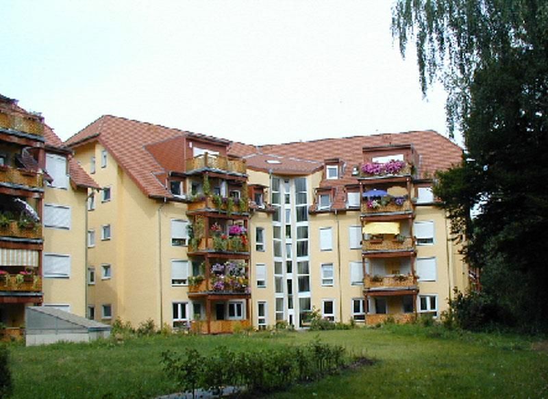 Ein großes gelbes Gebäude mit Balkonen und Blumen darauf