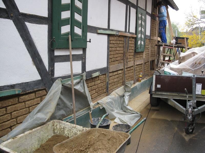 Eine Schubkarre voller Erde steht vor einem Backsteingebäude