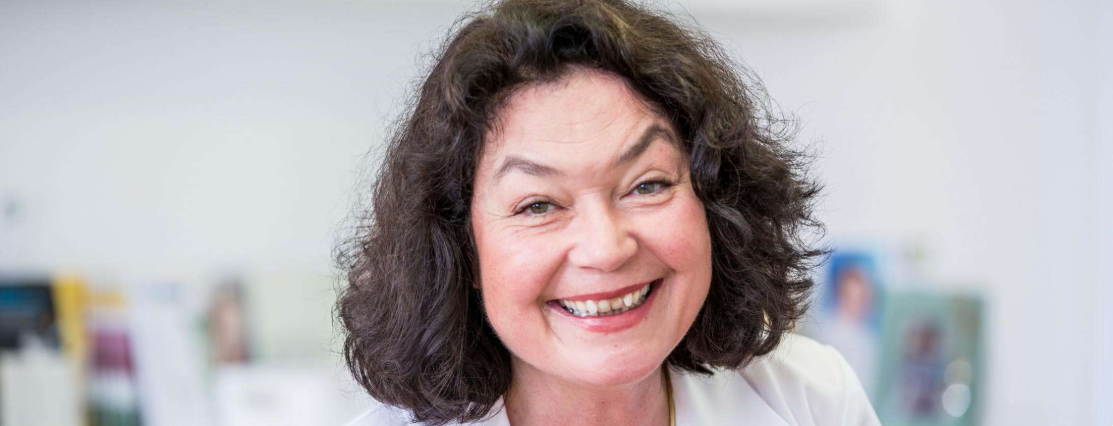 Eine Frau mit lockigem Haar lächelt in die Kamera.