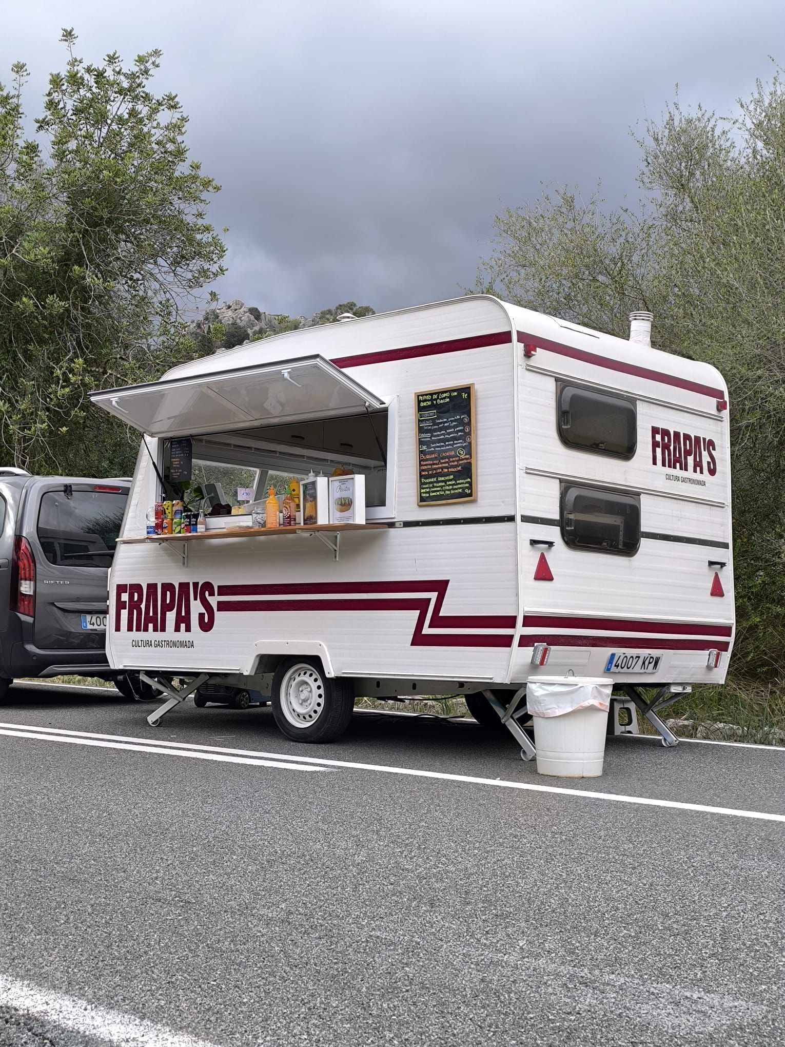 Un camión de comida que dice 'frumpy's' está estacionado al costado de la carretera.