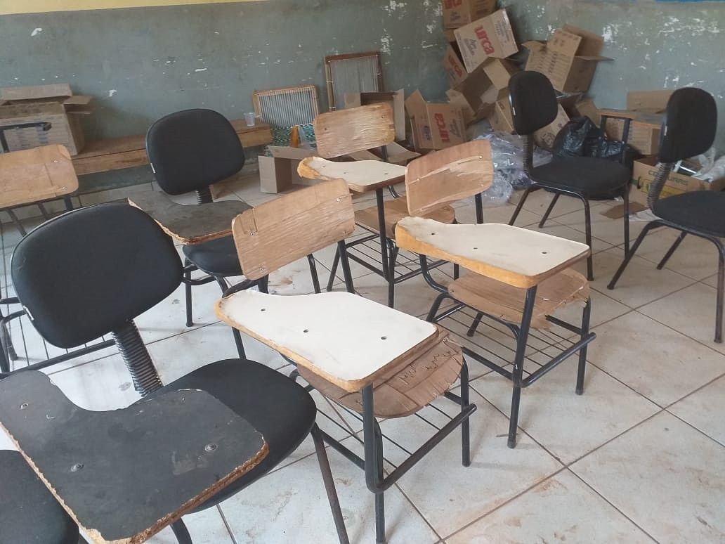 Leeres Klassenzimmer mit verstreuten schwarzen und hölzernen Stühlen auf einem gefliesten Boden