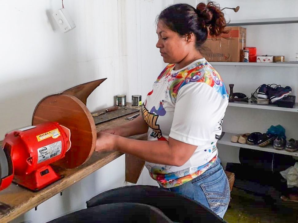 Eine Frau schärft in einer Werkstatt eine Klinge an einer Schleifmaschine.