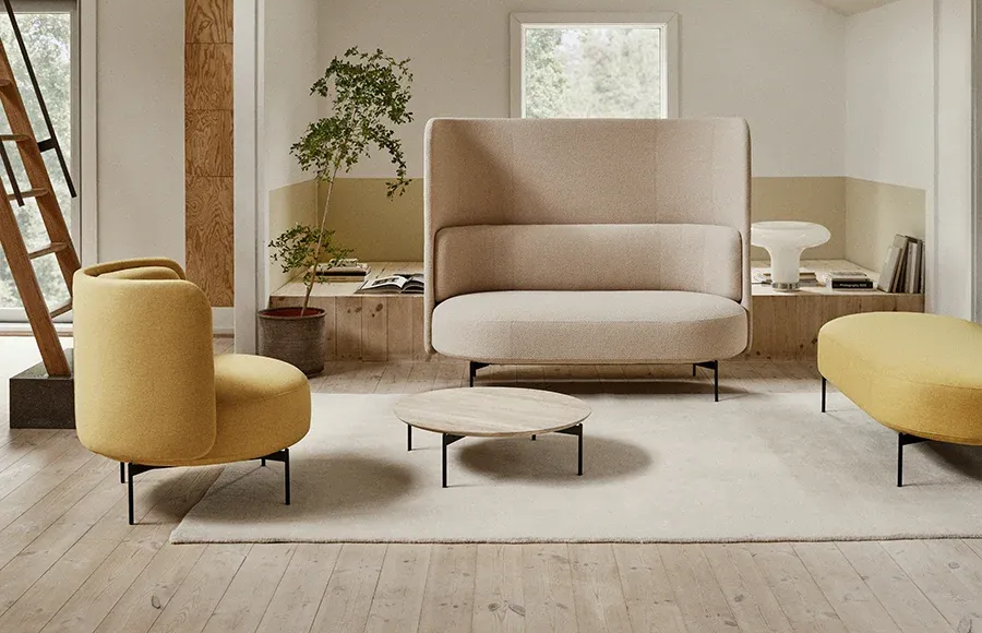 Sala de estar moderna con muebles beige y amarillo. Un sofá de respaldo alto y dos sillones rodean una mesa de centro baja.