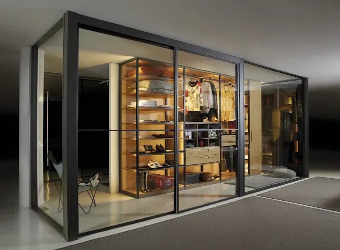 Vestidor con ropa colgada, cajones, estantes y equipaje en una habitación moderna en tonos neutros.