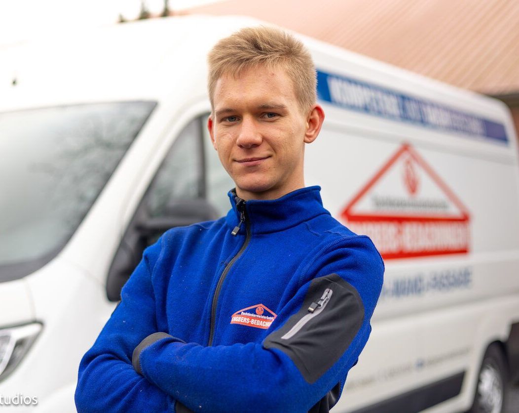 Ein Mann in einer blauen Jacke steht vor einem weißen Lieferwagen.