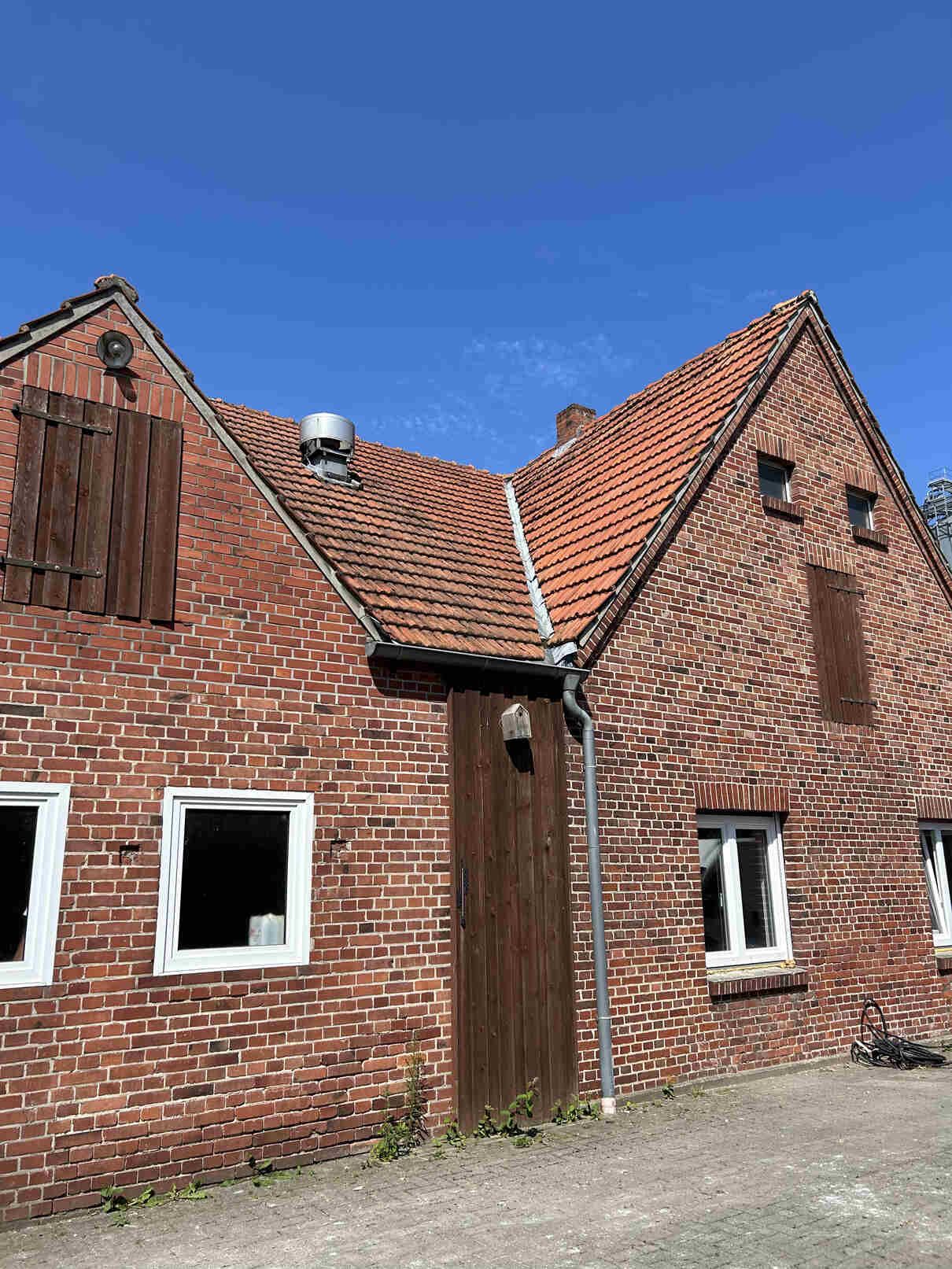 Ein Backsteinhaus mit rotem Ziegeldach und weißen Fenstern.