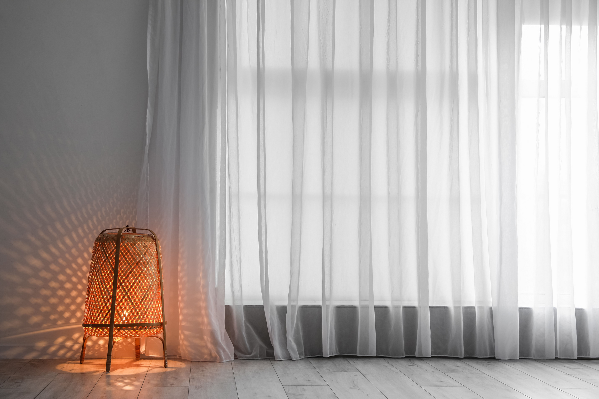 Hay una lámpara en el medio de la habitación con cortinas blancas.