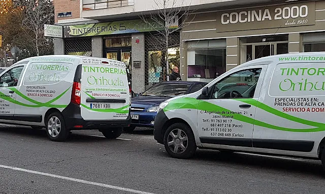 Dos furgonetas están aparcadas delante de un edificio que dice cocina 2000