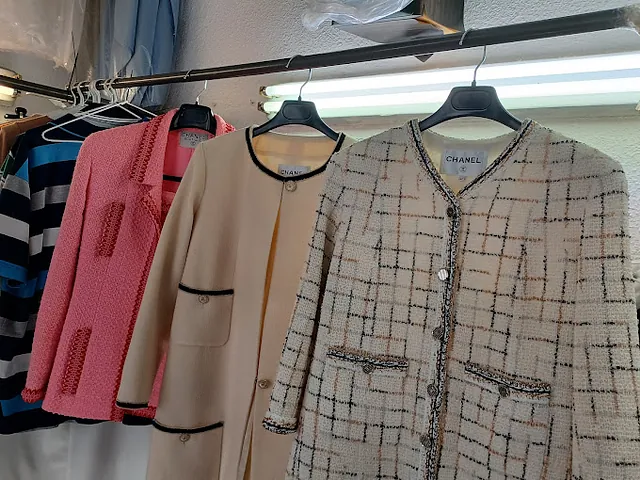 Una fila de chaquetas colgadas en un perchero con una que dice Chanel.