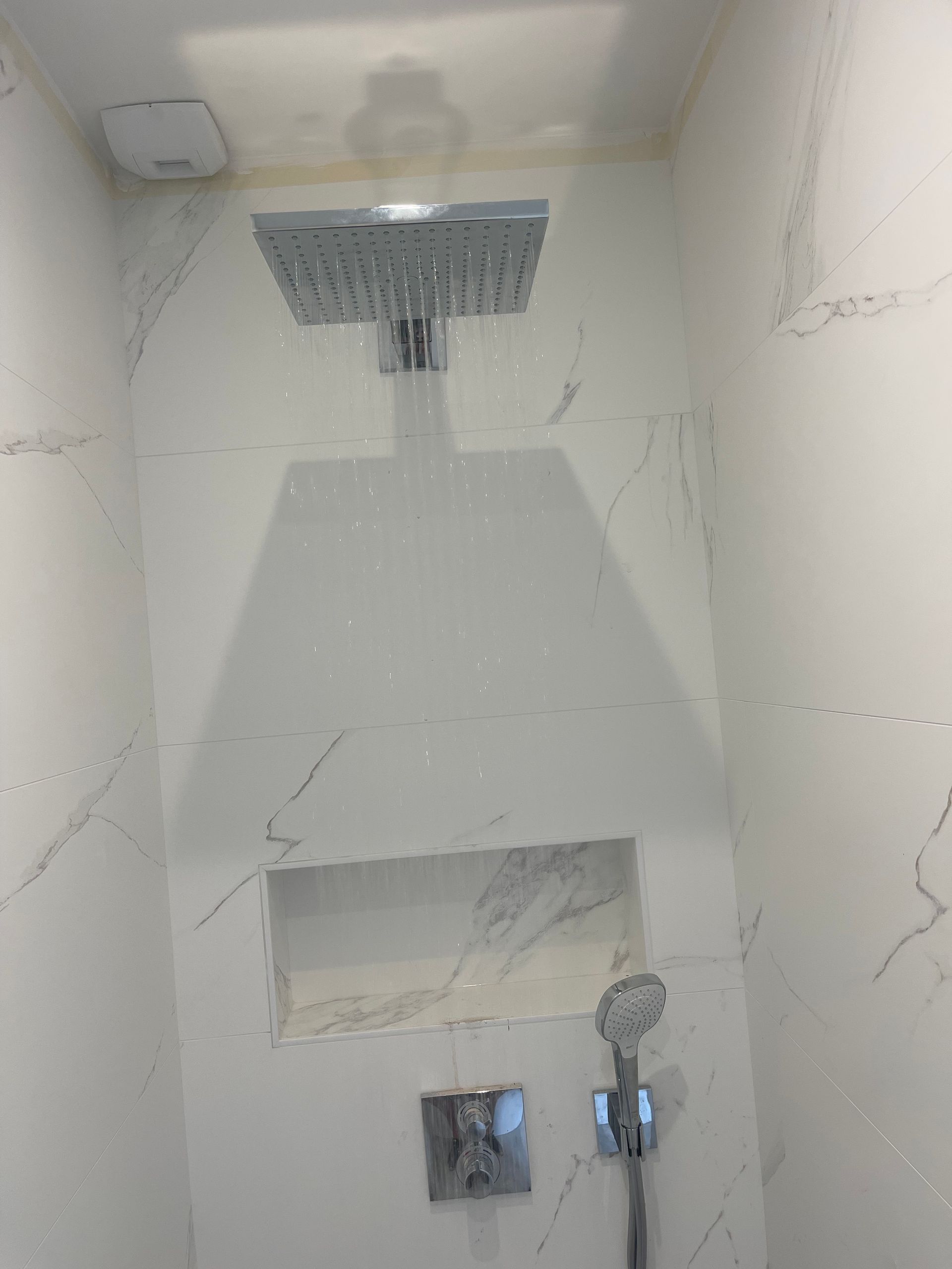 Eau qui coule de la colonne de douche dans une douche effet marbre