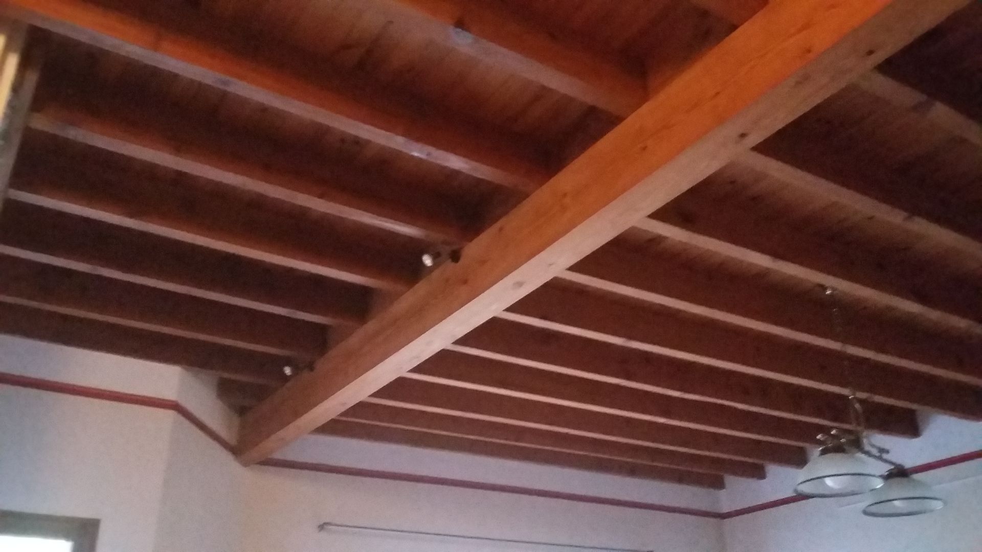 Un plafond vu du dessous en bois avec une poutre au centre