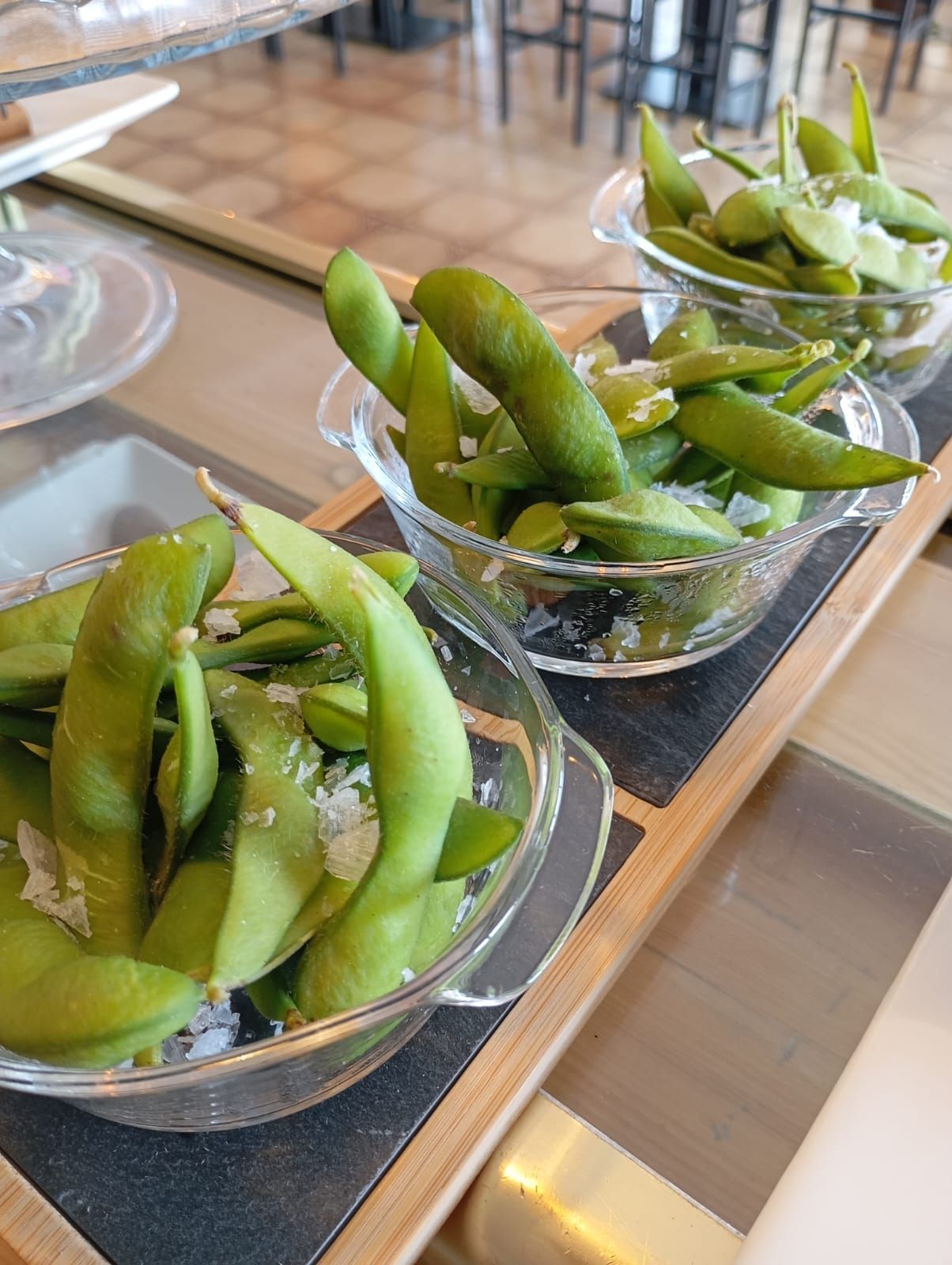 Una fila de cuencos llenos de judías verdes sobre una mesa.