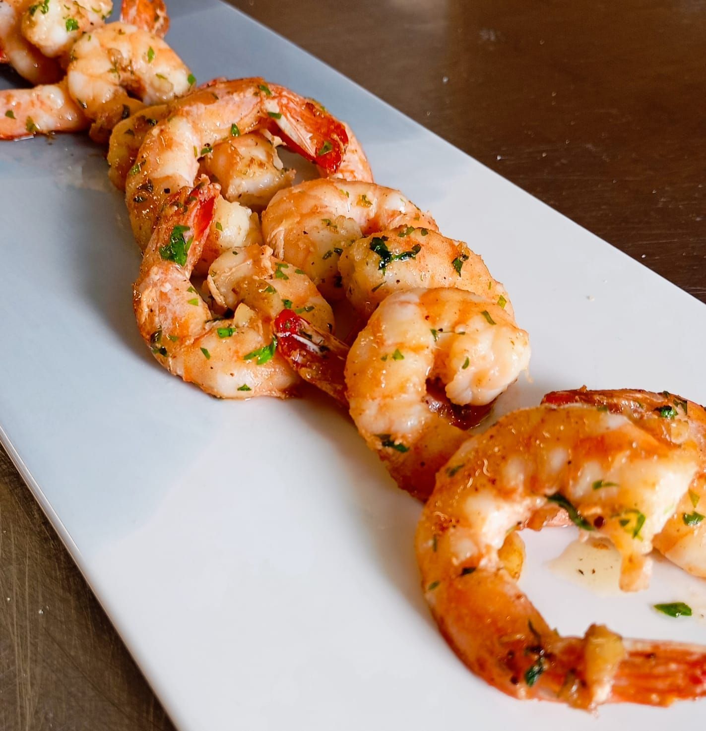 Una fila de camarones en un plato blanco sobre una mesa.
