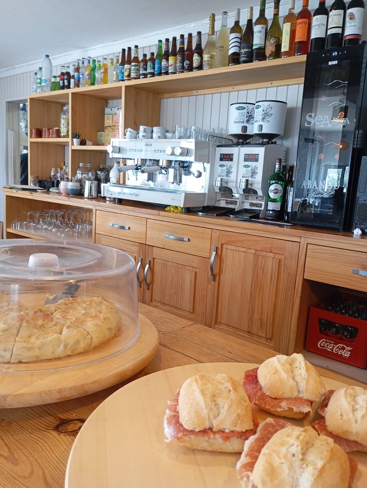 Una cocina con mucha comida y botellas en los estantes.
