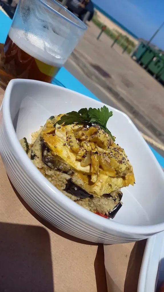 Un plato de comida está sobre una mesa al lado de un vaso de cerveza.