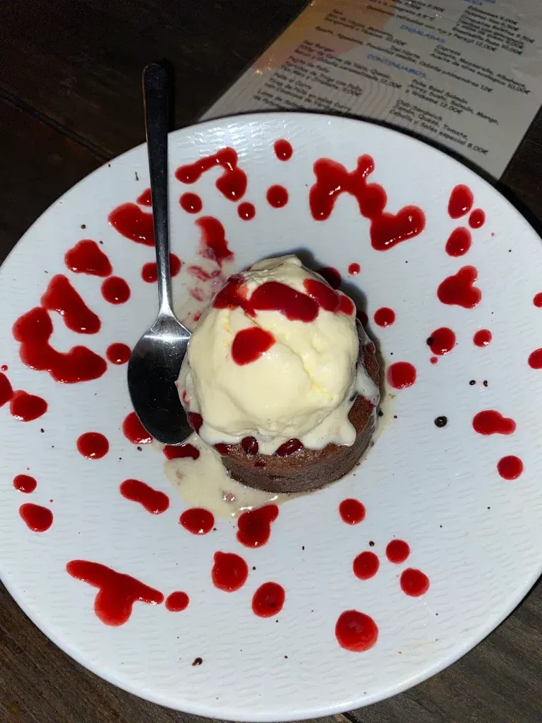 Un plato blanco cubierto con un brownie y helado.