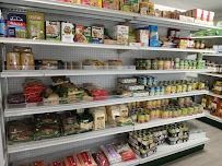 Die Regale im Supermarkt waren gefüllt mit verschiedenen verpackten Lebensmitteln, Gläsern und Waren, die in Reihen innerhalb eines hell erleuchteten Lebensmittelgangs angeordnet waren.