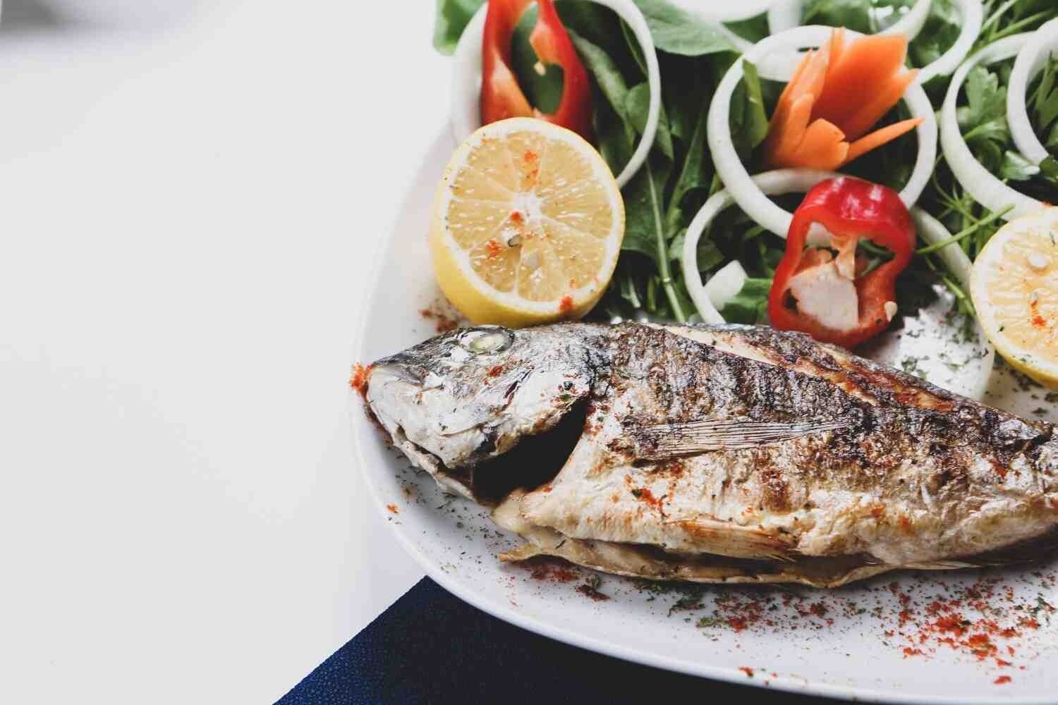 Pescado a la parrilla con camarones, mejillones, ensalada, tomates, pepinos y rábanos.