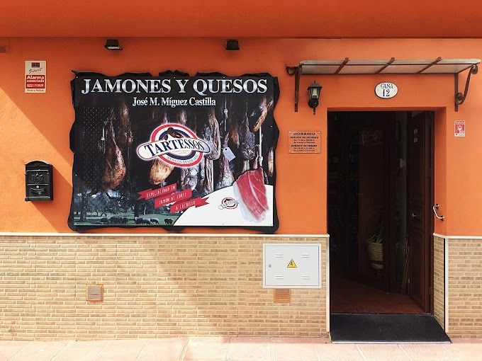 Un edificio naranja con un cartel que dice jamones y quesos.