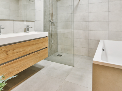 Salle de bain moderne avec vanité en bois, douche en verre, baignoire blanche et murs carrelés.